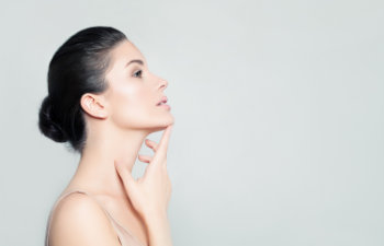 black haired woman touches her chin